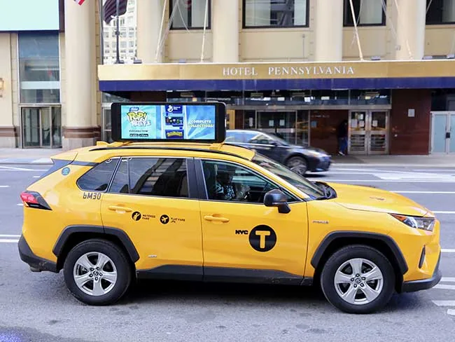 N3TWORK mobile-game digital LED taxi-top screen on an NYC yellow cab outside Hotel Pennsylvania, placed via Blue Line Media