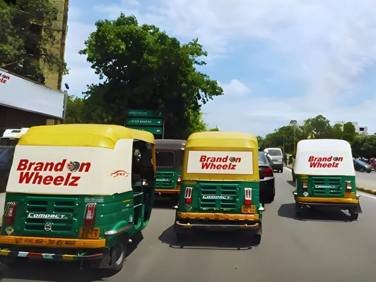 Fleet of auto-rickshaws on an Indian road with BrandOnWheelz rear-hood branding (operator's own auto-advertising inventory)