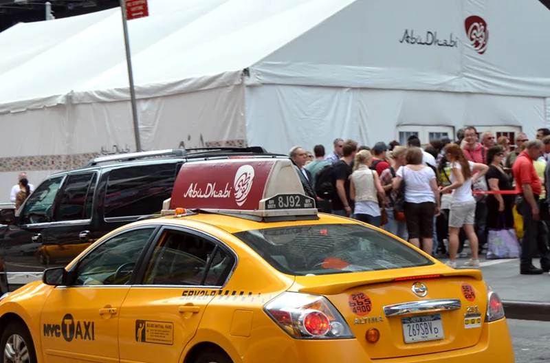 Abu Dhabi Tourism taxi-top on an NYC yellow cab at a street-level event tent activation — CVA Abu Dhabi case study