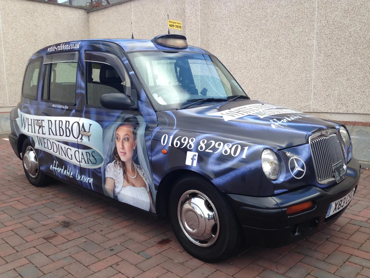 White Ribbon Wedding Cars full-body wrap on a Glasgow black-cab taxi, from Clyde Wraps' taxi advertising page.