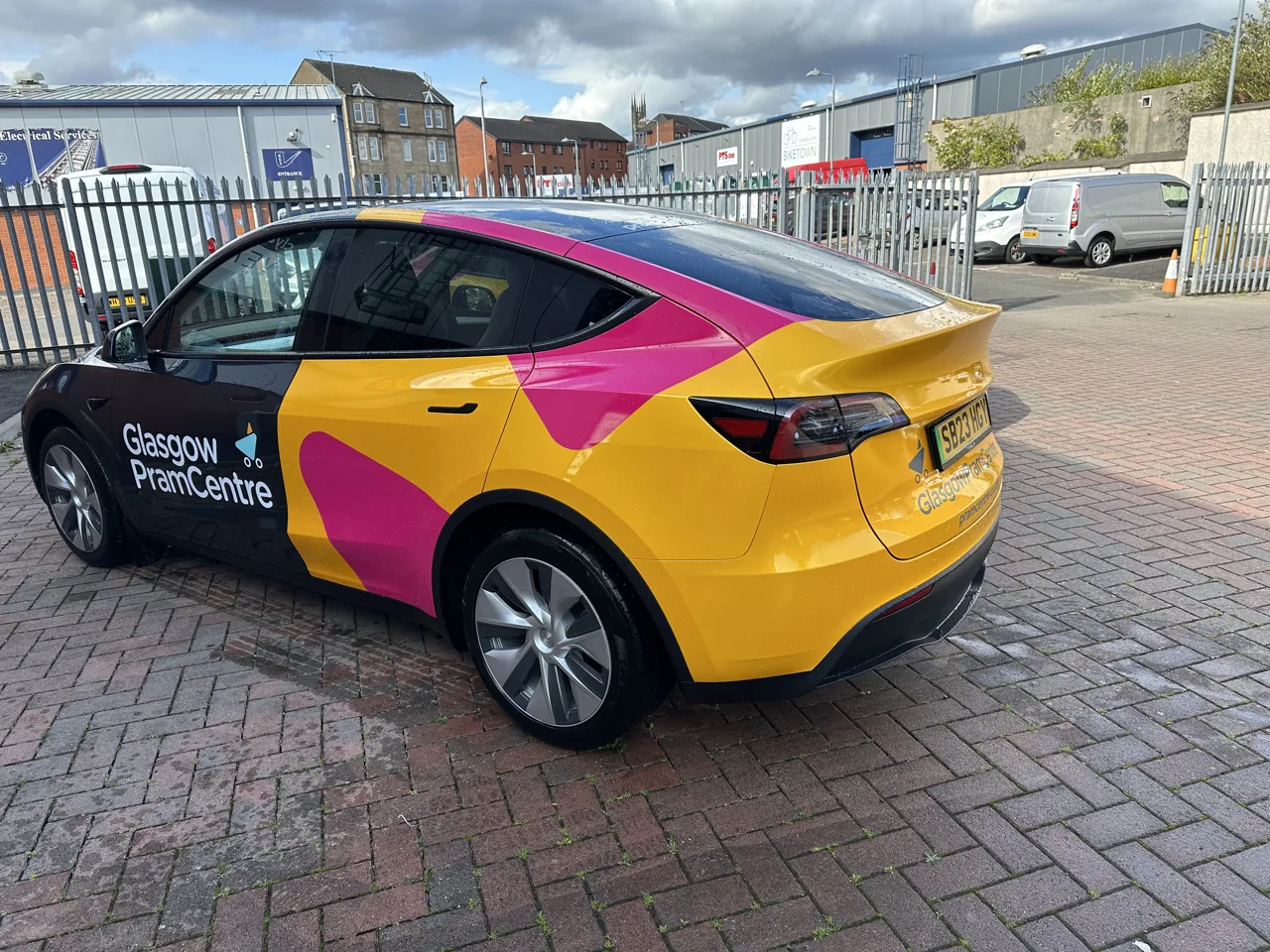 Glasgow Pram Centre pink/yellow full car wrap on a Tesla Model Y, from Clyde Wraps' homepage gallery.