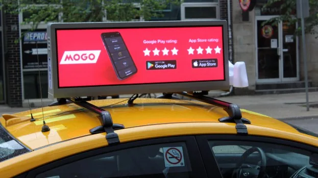 Taxi fitted with an Enroute View Media rooftop LED display in traffic