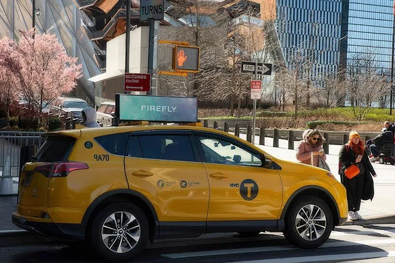 Firefly lit digital taxi/rideshare rooftop top displaying an ad campaign