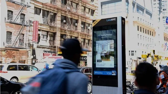 Passersby at a LinkNYC kiosk running the StreetEasy DOOH campaign, NYC