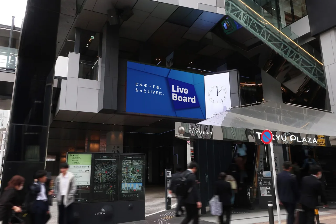 LIVE BOARD large-format digital OOH screen at Shibuya Fukuras / Tokyu Plaza entrance (Fukuras Vision Set), Tokyo — street-level photo with pedestrians, screen showing LIVE BOARD creative.