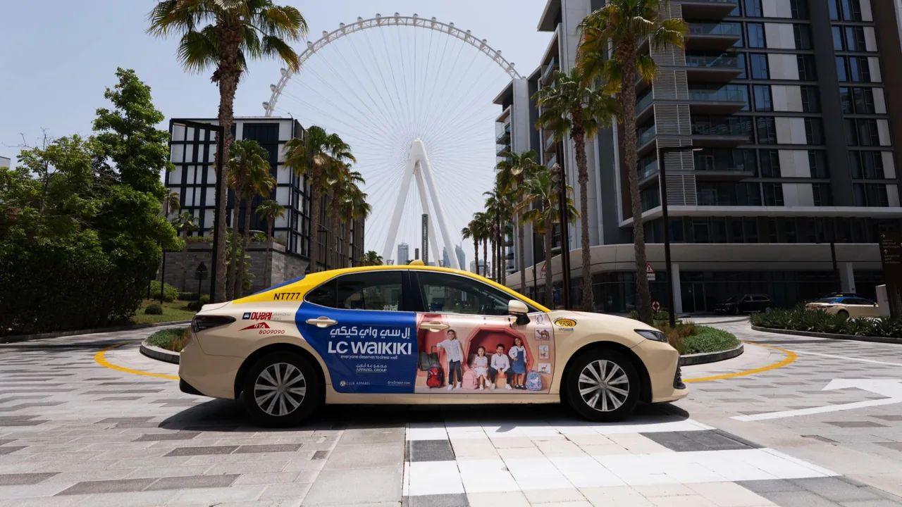 LC Waikiki full-body wrap on a cream Dubai RTA taxi in front of Ain Dubai (marketplace listing photo)