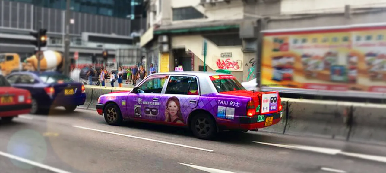 Full-body Hong Kong taxi wrap for a beauty/skincare brand, photographed in street traffic (Media Savvy taxi advertising)