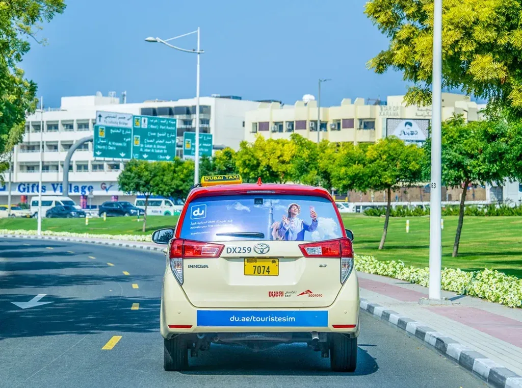 du telecom 'tourist eSIM' rear-window and bumper taxi branding on a Dubai Taxi Innova