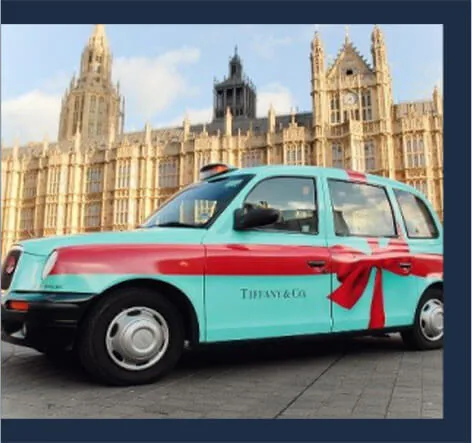 Tiffany & Co. turquoise taxi wrap (with red-bow graphic) on a London cab outside the Houses of Parliament, from Movia Media's taxi advertising page.
