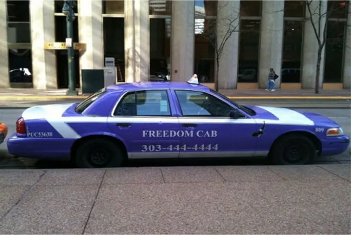 Freedom Cab purple sedan taxi wrap (Denver) parked kerbside, shown on Movia Media's taxi advertising page.