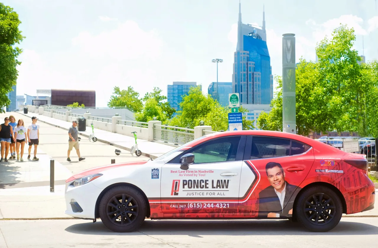 Ponce Law partial car wrap on a red-and-white Mazda sedan on a Nashville street - Nickelytics rideshare wrap