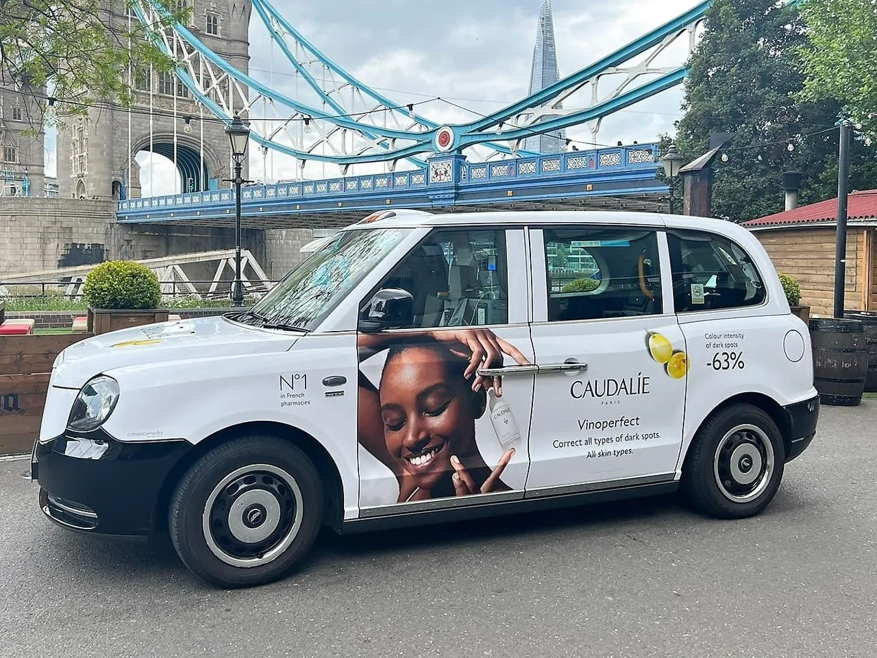 Caudalie Vinoperfect full-livery wrap on a London electric taxi (LEVC TX) at Tower Bridge, One Day agency taxi advertising