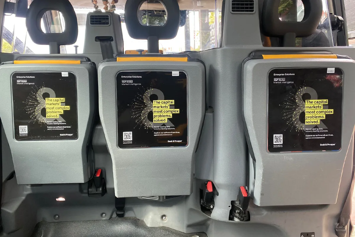 S&P Global Market Intelligence 'Seek & Prosper' tip-seat ads on the folding backseats inside a London taxi