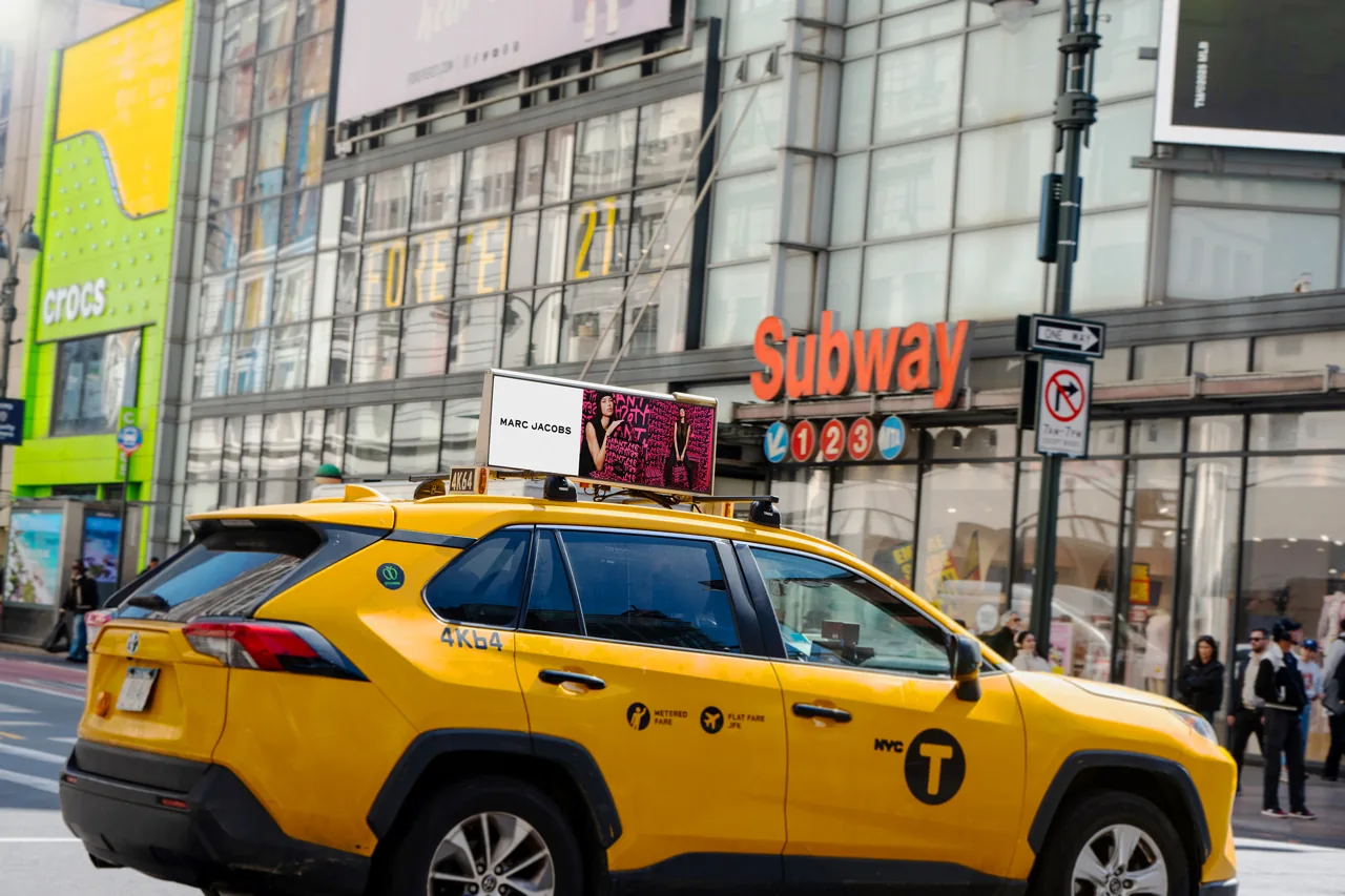 NYC yellow cab carrying a SOMO digital taxi-top screen (programmatic DOOH example)