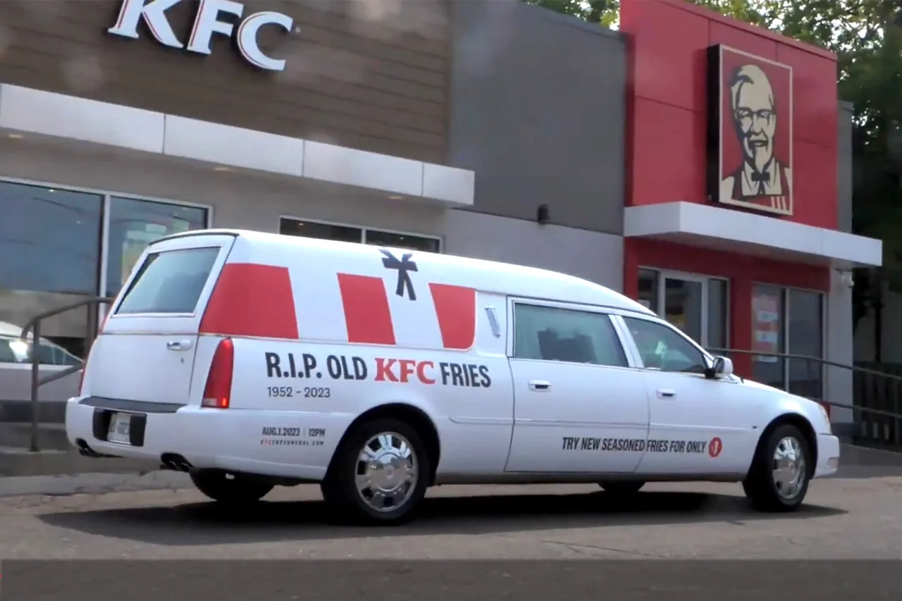 KFC 'R.I.P. Old KFC Fries' branded hearse vehicle wrap parked outside a KFC (Statements Media)