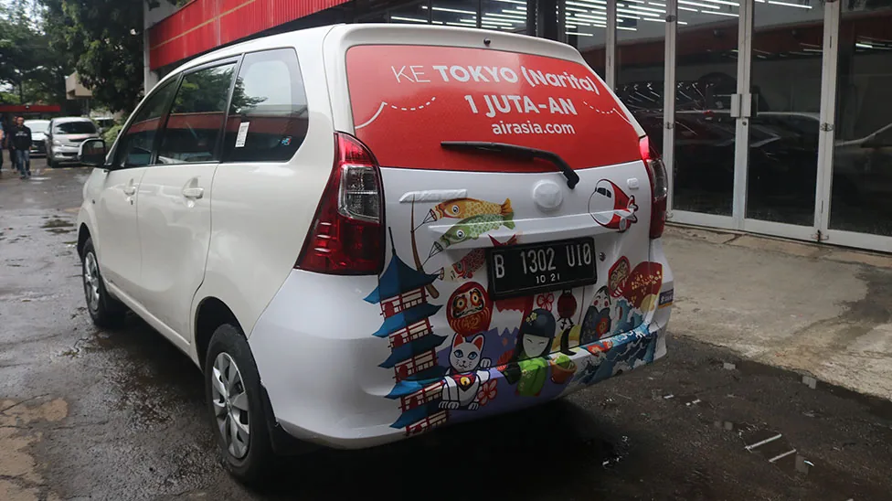 AirAsia 'Ke Tokyo (Narita)' full back-panel wrap on a white MPV rideshare car (StickEarn StickMob) — StickEarn's own showcase gallery.