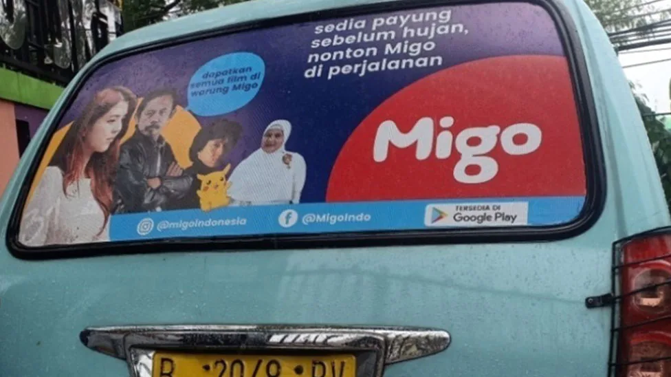 Migo rear-window branding on an angkot public minibus (StickEarn StickAngkot) — StickEarn's own showcase gallery.