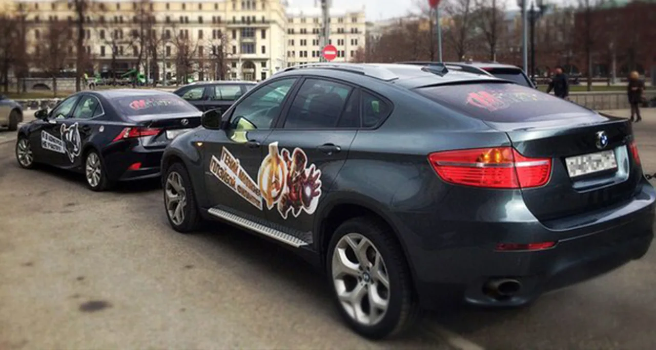StickerRide fleet running a Marvel 'Avengers' campaign - side-body decals on a BMW X6 and a sedan on a Moscow street.