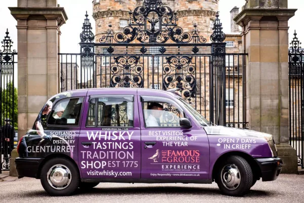 The Famous Grouse / Glenturret whisky purple full-livery taxi wrap outside a heritage gate in Edinburgh (The Ark Marketing & Media own work)