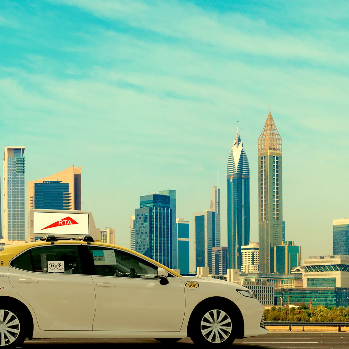 Dubai RTA taxi carrying a rooftop digital LED display, shot against the Dubai skyline