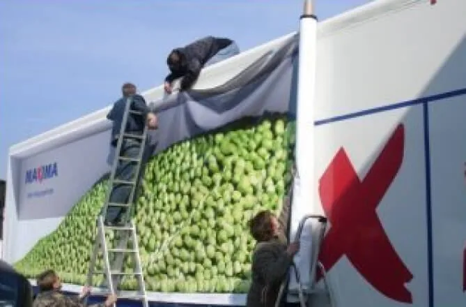 Installers applying the Maxima green-apple trailer graphic wrap (TruckAds fleet-graphics install)
