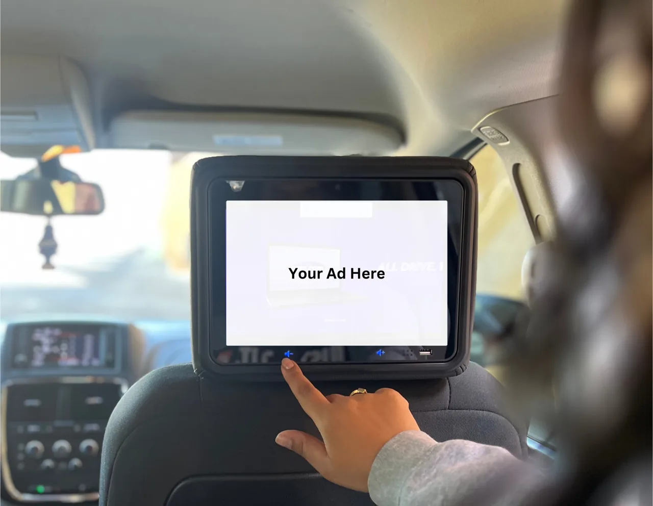 In-car Vugo passenger screen displaying an ad-creative slot ('Your Ad Here'), physical in-vehicle context (Vugo official site)