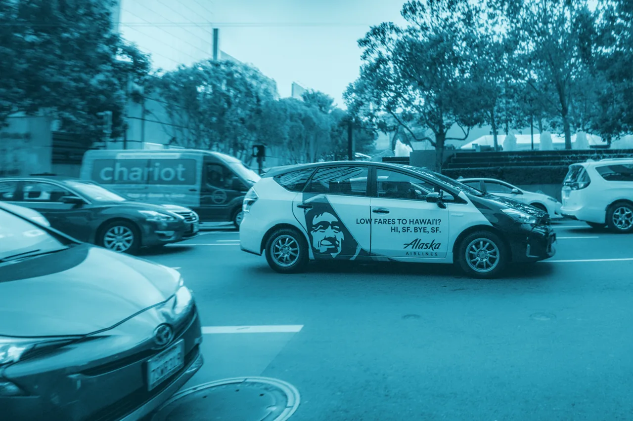 Alaska Airlines 'Low Fares to Hawaii' side-panel wrap on a rideshare Toyota Prius in San Francisco traffic