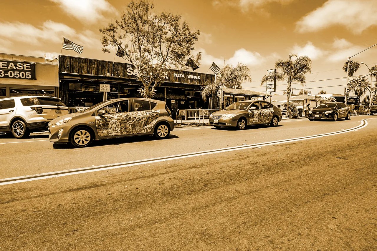 Ballast Point Brewing side-panel wraps on rideshare cars driving a San Diego street